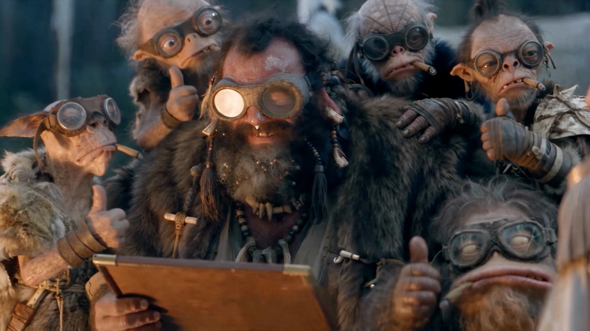 Red-skinned goggled Thump surrounded by Bobos holding a clipboard